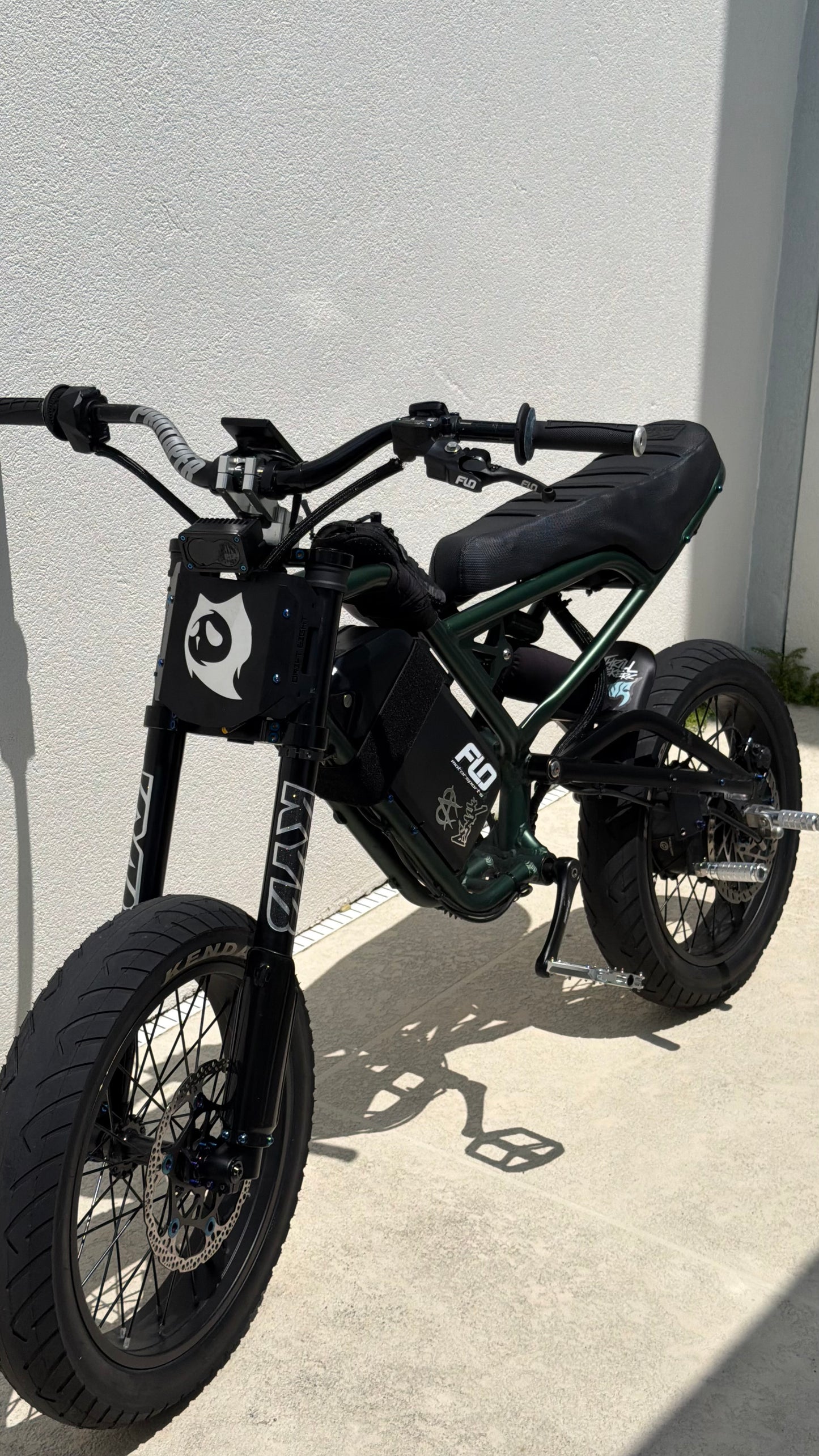 green electric bike parked on a concrete surface with a white wall in the background