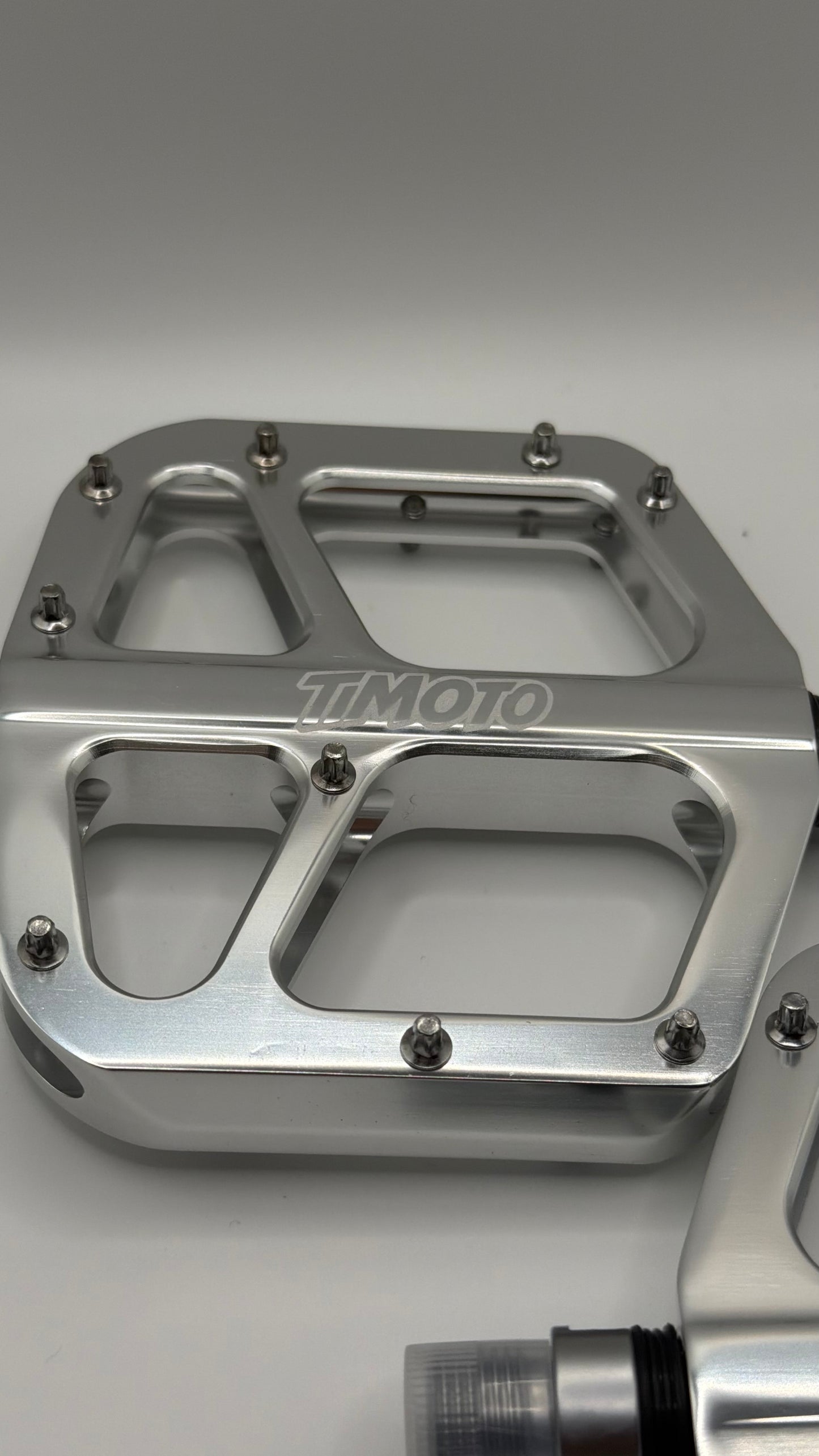 Metallic foot peg with 'TIMOTO' branding on a gray background