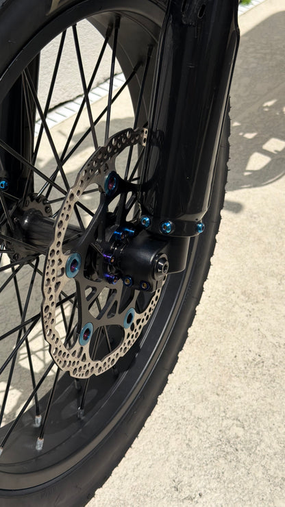 Close-up of a bicycle wheel with disc brake system on a road.