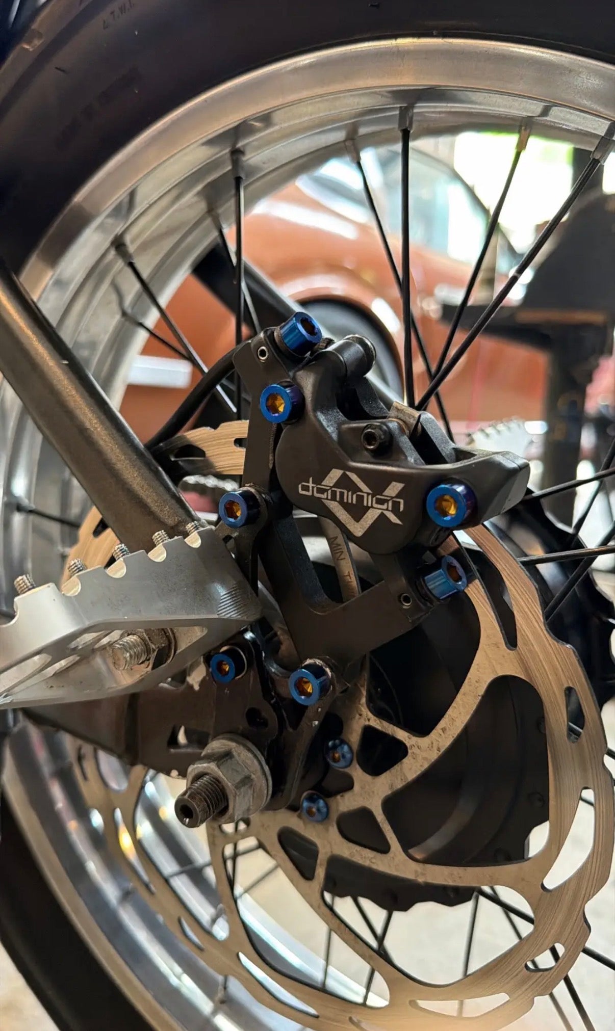Close-up of a motorcycle wheel with disc brake and 'Dominion' branding.
