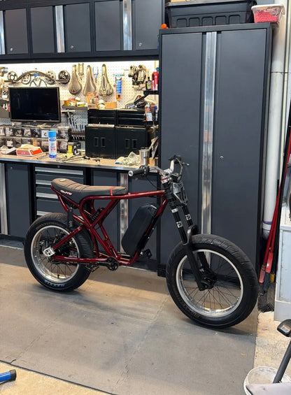 Red electric bike in a workshop setting with tools and equipment in the background